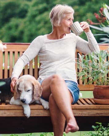 Older woman sitting a bench drinking coffee